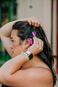 Woman adjusting pink cochlear implant 
