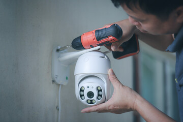 Man installing home wireless CCTV camera installing security equipment water proof cover to protect...