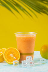 Vertical de jugo de naranja con papaya en un fondo amarillo