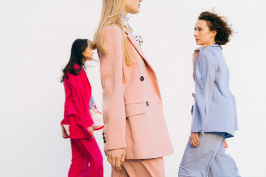 different women in colored suits walk along the walls
