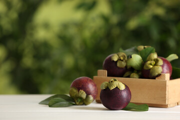 Delicious ripe mangosteen fruits on white wooden table outdoors, space for text