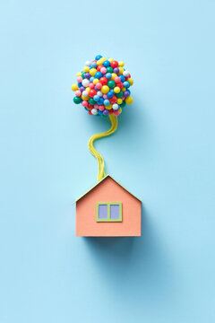 Papercraft house model with balloons on blue background