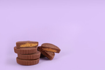 Sweet peanut butter cups on violet background. Space for text