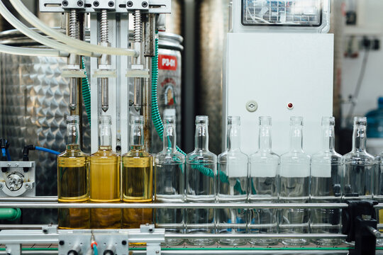 Full And Empty Bottles Of Alcohol On Production Line - Powered by Adobe