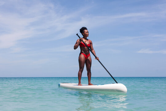 Focused woman standing on SUP board in sea