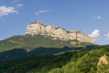 Fototapeta na wymiar Rock formation in pyrenees under blue summer sky with green forest in foreground
