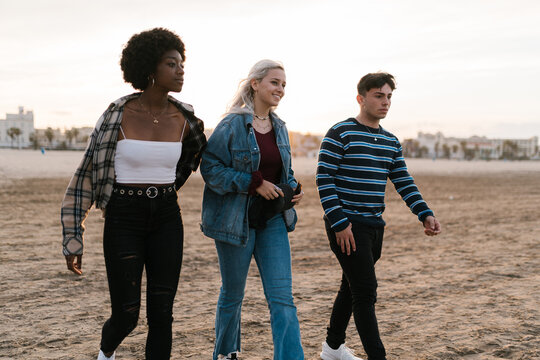 Multiracial friends walking on sandy beach