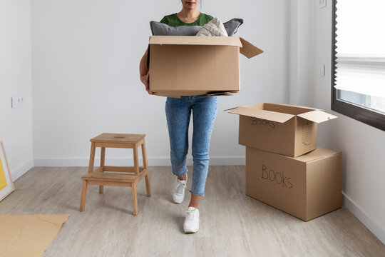 Detail of woman carrying a moving box at new home