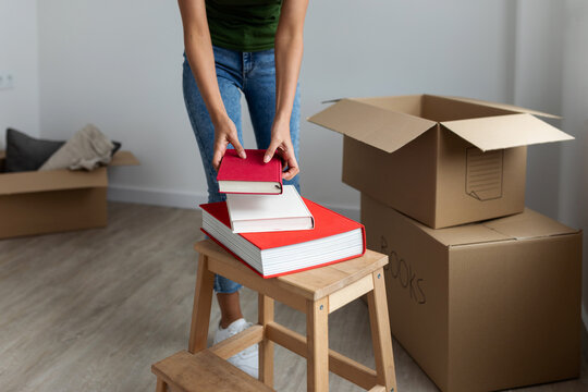 Detail of woman unpacking moving boxes with books