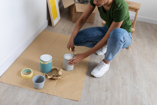 Woman opening a tin of paint on the floor at new home