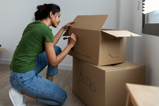 woman writing in a box at new apartment