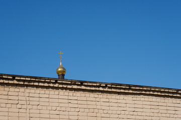 The dome of the church behind the brick wall against the clear blue sky.
