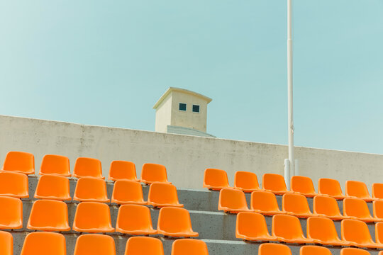 The orange color bleachers are empty inside the stadium