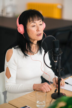 Asian woman recording podcast in modern studio