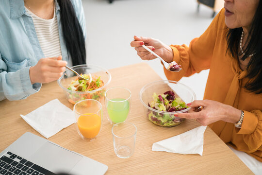 Crop women having lunch during work