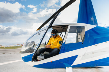 Helicopter pilot with sunglasses checking the smartphone