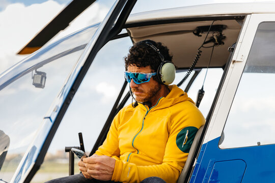 Helicopter pilot with sunglasses checking the smartphone
