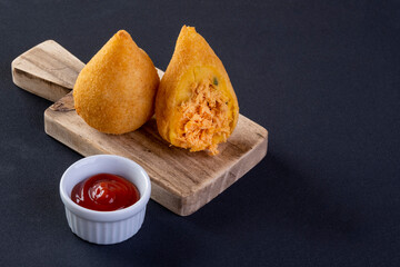Coxinha on wooden board with black background