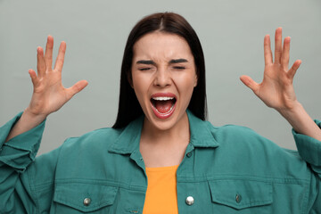 Angry young woman on grey background. Hate concept