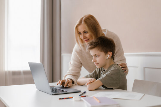 Mother and child doing homework together and using laptop