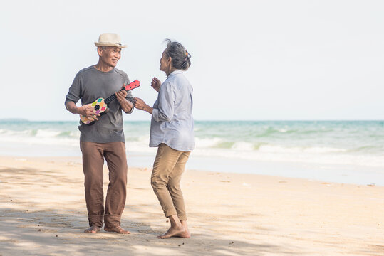 Happy senior couple relaxing outdoors singing and playing acoustic guitar at beach near sea sunny day, Mature man playing ukulele for his wife at sea, plan life insurance at retirement couple concept