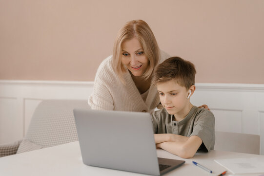 Mother and child doing homework together and using laptop