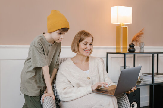 Mother and son using laptop in armchair