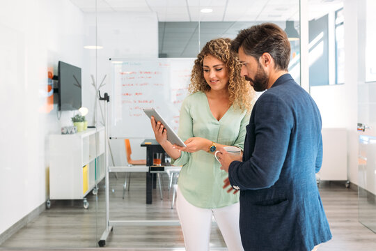 Beautiful blonde woman showing documents on a tablet to her boss