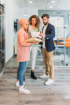 Smiling multiracial coworkers talking during coffee break in office