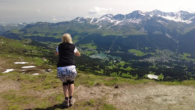 backside of a woman jumping in SLOW MOTION on Piz Scalottas top. Tourist resort in Plessur Alps of Switzerland in Grisons.
