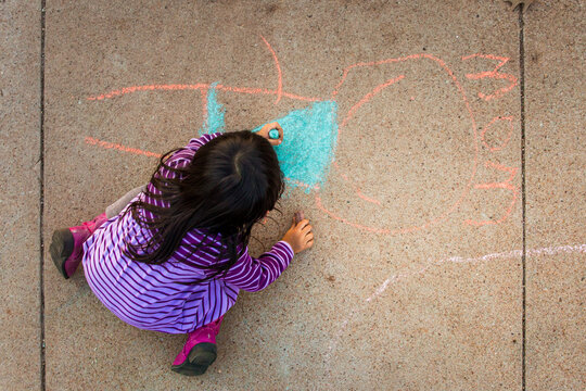 Girl from above chalk drawing a Mom figure