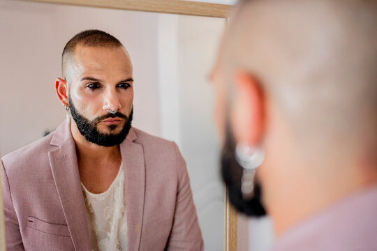 Beautiful man with makeup looking at mirror