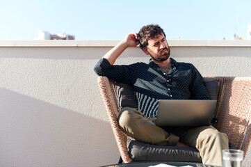 Man thinking while working online on his patio