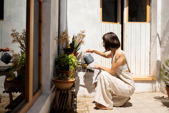 Young woman watering plants at home