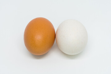 Two eggs of different color, one brown and one white, isolated on a white background.