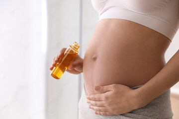 Young pregnant woman with cosmetic product indoors, closeup. Space for text - obrazy, fototapety, plakaty