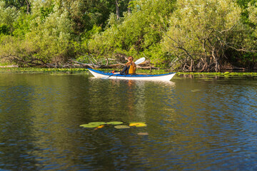 Sea kayak paddled by a young woman with long hair wearing a personal floation device 