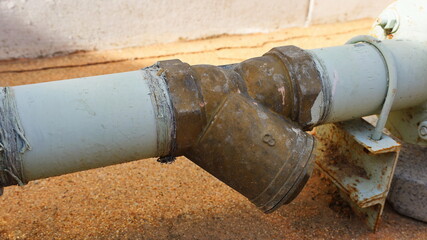 Brass Y-Strainer Closeup. The old Y-Strainer on the white pipe is a device for trapping debris or...