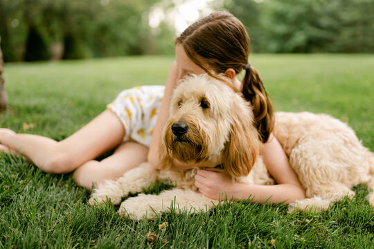 tween girl cuddling her pup on the grass