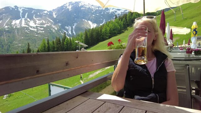 tourist girl drinking a draft beer on top Pradaschier park station of Churwalden town of Switzerland. Famous tourist resort for climbing activities and toboggan run in Grisons canton.