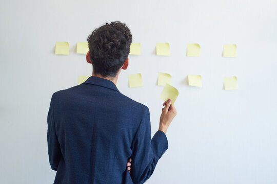 Young Man From Behind Plans With Post It On White Background