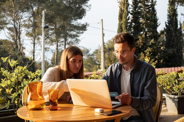 Happy couple buying online using credit card on terrace 