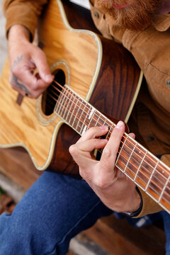 Crop guy playing guitar outside house