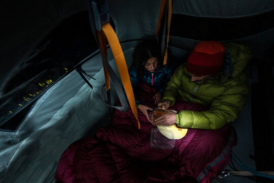 Climbers eating pizza inside a wall portaledge at night