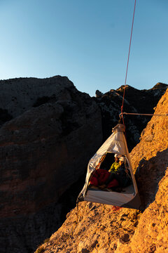 Climbers resting inside a wall portaledge at mountain