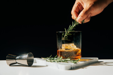 hand garnishing a glass of whiskey