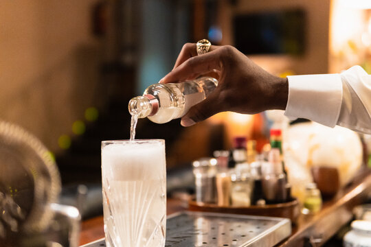Crop barman adding alcohol drink in cocktail