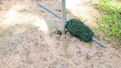 Roll the green rope on the ground. Plastic rope wrapped on a gray pipe spool beside the pole on a ground grass background with copy space. Selective focus