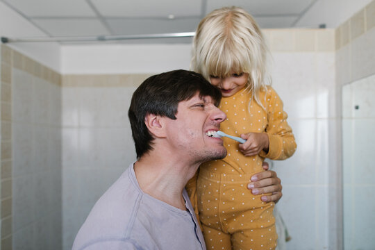 Daughter helps his father brush his teeth
