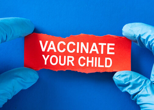 Doctor holds a red paper with the word VACCINATE YOUR CHILD,